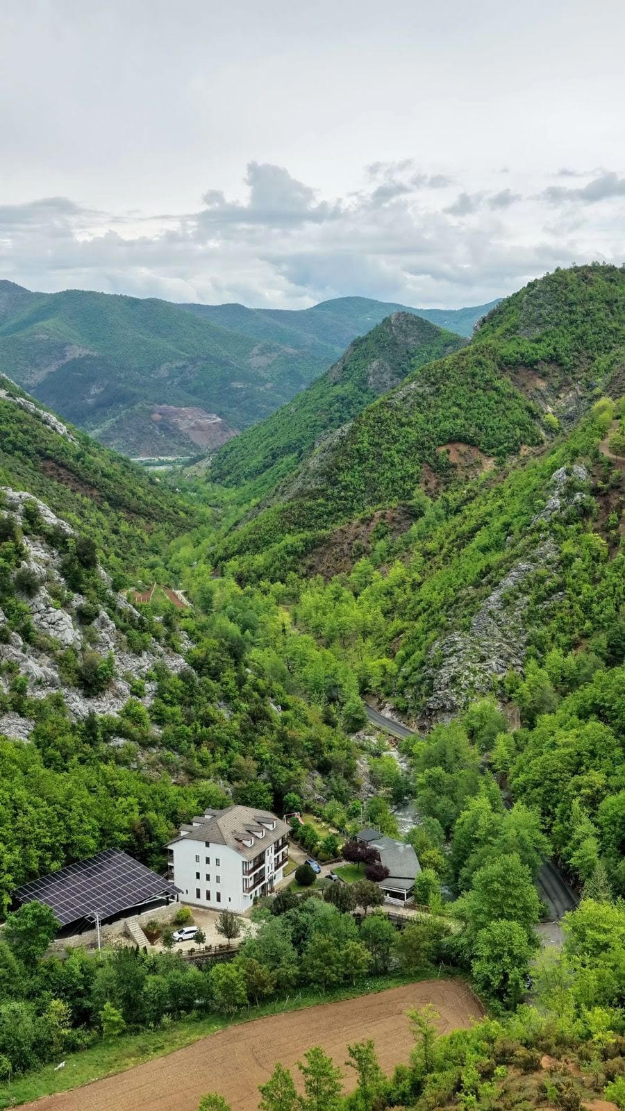 Il lato dell'hotel davanti a un ripido pendio boscoso e a una parete di roccia